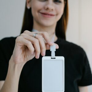 Portrait of a cheerful woman holding a blank ID badge, perfect for business or event promotion.